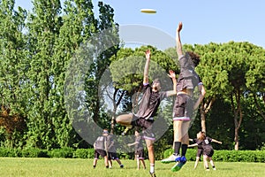 Group of young teenagers people in team wear playing a frisbee game in park oudoors. jumping man catch a frisbee to a teammate in photo