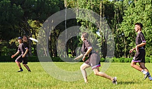 Group of young teenagers people in team wear playing a frisbee game in park oudoors. man tosses a frisbee to a teammate in an