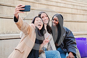 Group of young woman having fun doing a selfie with smartphone. Three multiracial happy girls amiling taking a photo