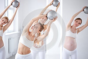 group of young women of caucasian appearance doing exercises with balls, in fitness studio