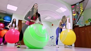 A group of young women doing exercises with fitballs in a fitness club.