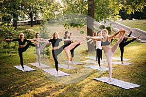 Group of young women are doing yoga exercise with left arm and leg outstretched