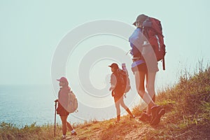 Group young women of hikers walking with backpack on a mountain at sunset.