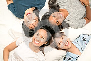 Group of young women lying in bed, happy and smiling, top view