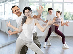 Group of young women and men enjoying active dance movement in studio