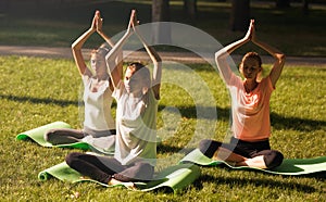 Group of young women practicing yoga, morning meditation in nature at the park