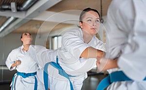 Group of young women practising karate indoors in gym.