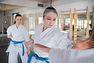 Group of young women practising karate indoors in gym.