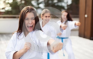 Group of young women practising karate outdoors on terrace.