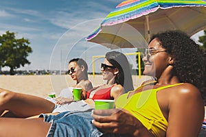 Group of young women resting on the beach, sunbathing on bright summer day