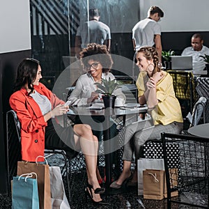 group of young women with shopping bags drinking coffee