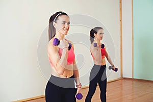 Group of young women in sportswear with dumbbells exercising at the gym.