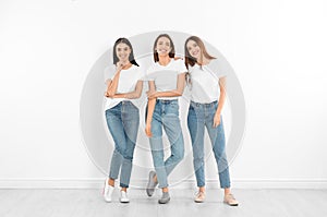 Group of young women in stylish jeans near wall photo