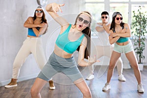 Group of young women and young guy in sunglasses dancing hip hop
