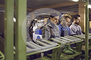 Group of young workers working in manufacturing workshop at footwear making factory