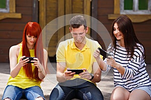 Group of youth laughing addicted to playing mobile video game ou