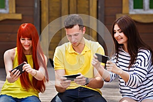 Group of youth laughing playing mobile video game outdoors