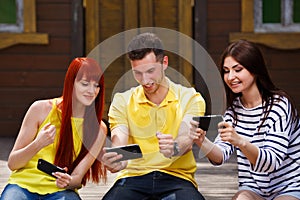 Group of youth laughing playing mobile video game outdoors, guy