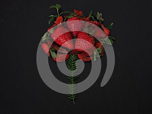 Grouped strawberries imitating a flower on a black plate