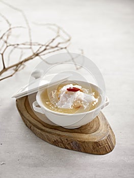 Grouper Fillet in Winter Melon and Conpoy Soup Served in a bowl isolated on wooden board side view on grey background