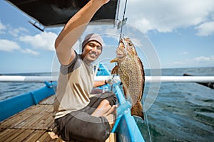 A grouper is hooked while fishing with a fishing rod