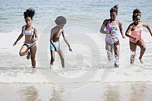 Groupmboys and girls running and makeing splashes in shallow sae water, cute kids having fun on sandy summer beach, happy