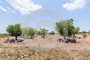 Groups of people sitting under the trees for shade