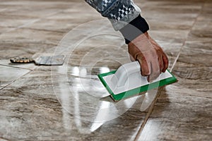 Grouting ceramic tiles. Tilers filling the space between tiles using a rubber trowel. photo