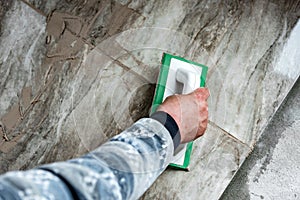 Grouting ceramic tiles. Tilers filling the space between tiles using a rubber trowel. photo