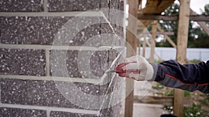 Grouting seams on the facade of the building with a trowel. A worker levels the seams with a trowel on the facade tiles