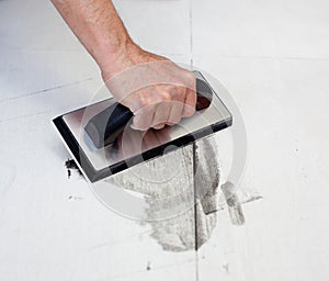 Grouting tiles with rubber trowel man hand