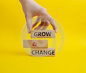 Grow and Change symbol. Concept word Grow and Change on wooden blocks. Businessman hand. Beautiful yellow background. Business and