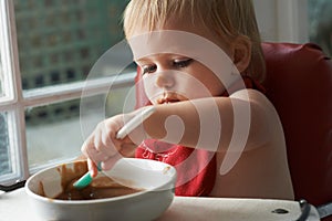 Growing boy needs his food. A young baby boy eating to his hearts content in his high chair.