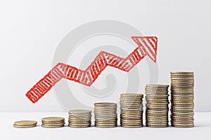 Growing chart of gold coins with drawing red arrow