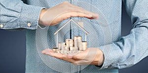 Growing coins house on stack coins in hand. Concept of Investment propert