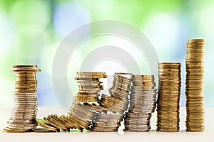 Growing coins stacks with green and blue sparkling bokeh backgro