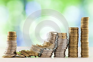 Growing coins stacks with green and blue sparkling bokeh backgro