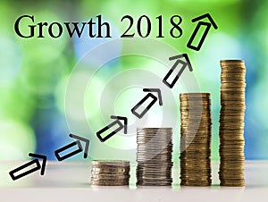 Growing coins stacks with green and blue sparkling bokeh background and words Growth 2018