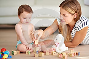 Growing and learning is childs play. an adorable baby girl and her mother playing with wooden blocks at home.