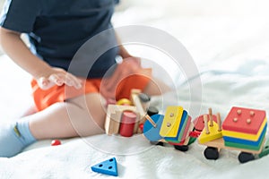 Growing up and kids leisure concept. A child playing with a colored wooden train. Kid builds constructor. Without face. Selective