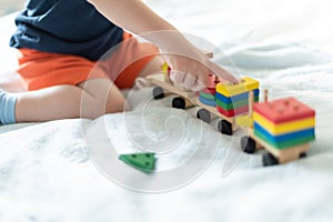 Growing up and kids leisure concept. A child playing with a colored wooden train. Kid builds constructor. Without face. Selective