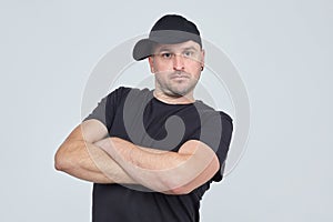 Grown man in a black cap and t shirt crossed his arms over his chest