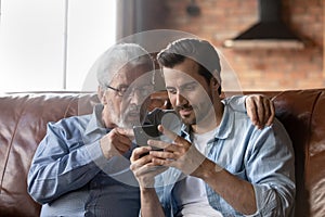 Grown son teaching elderly 70s dad to use mobile app