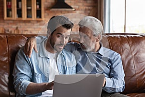 Grown son teaching senior father to use online apps