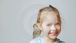 Grown up starling nestling sit on shoulder of little girl and sing with open beak. Portrait of happy child on gray.