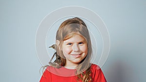 Grown up starling nestling sitting on shoulder of smiling little girl. Portrait of happy child on gray. Spring songbird.