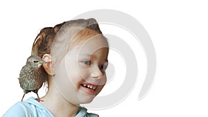 Grown up starling nestling sitting on shoulder of smiling little girl. Portrait of happy child isolated on white.