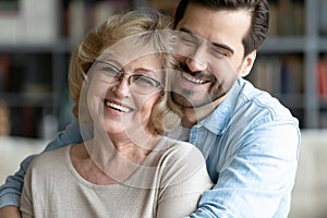 Grownup son hugs elderly mother laughing joking enjoy time together