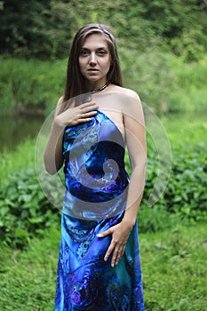 Growth portrait of a girl in a blue dress in the middle of a meadow