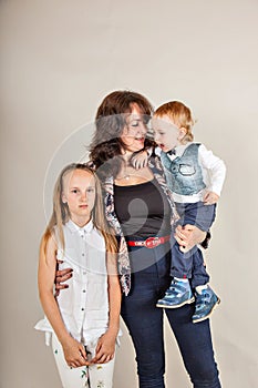 Growth portrait of happy mother with two children isolated gray background.